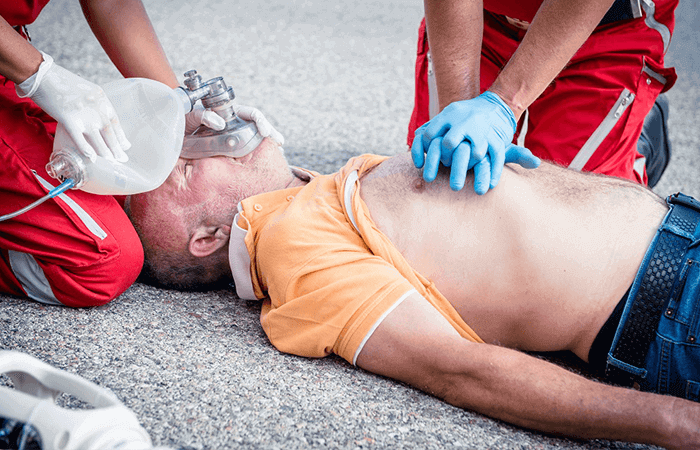 Man with oxygen mask getting CPR on the ground